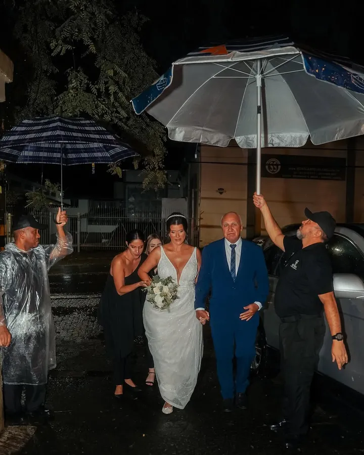 Noivos chegando ao casamento sob guarda-chuvas da equipe Borba