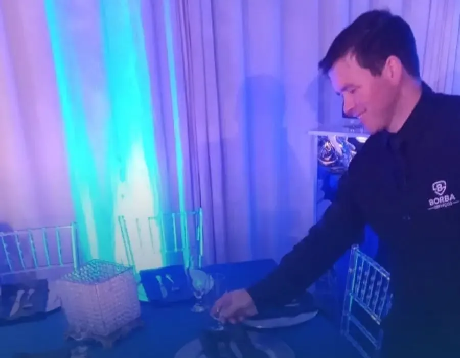 Garçom da Borba servindo mesa em salão iluminado